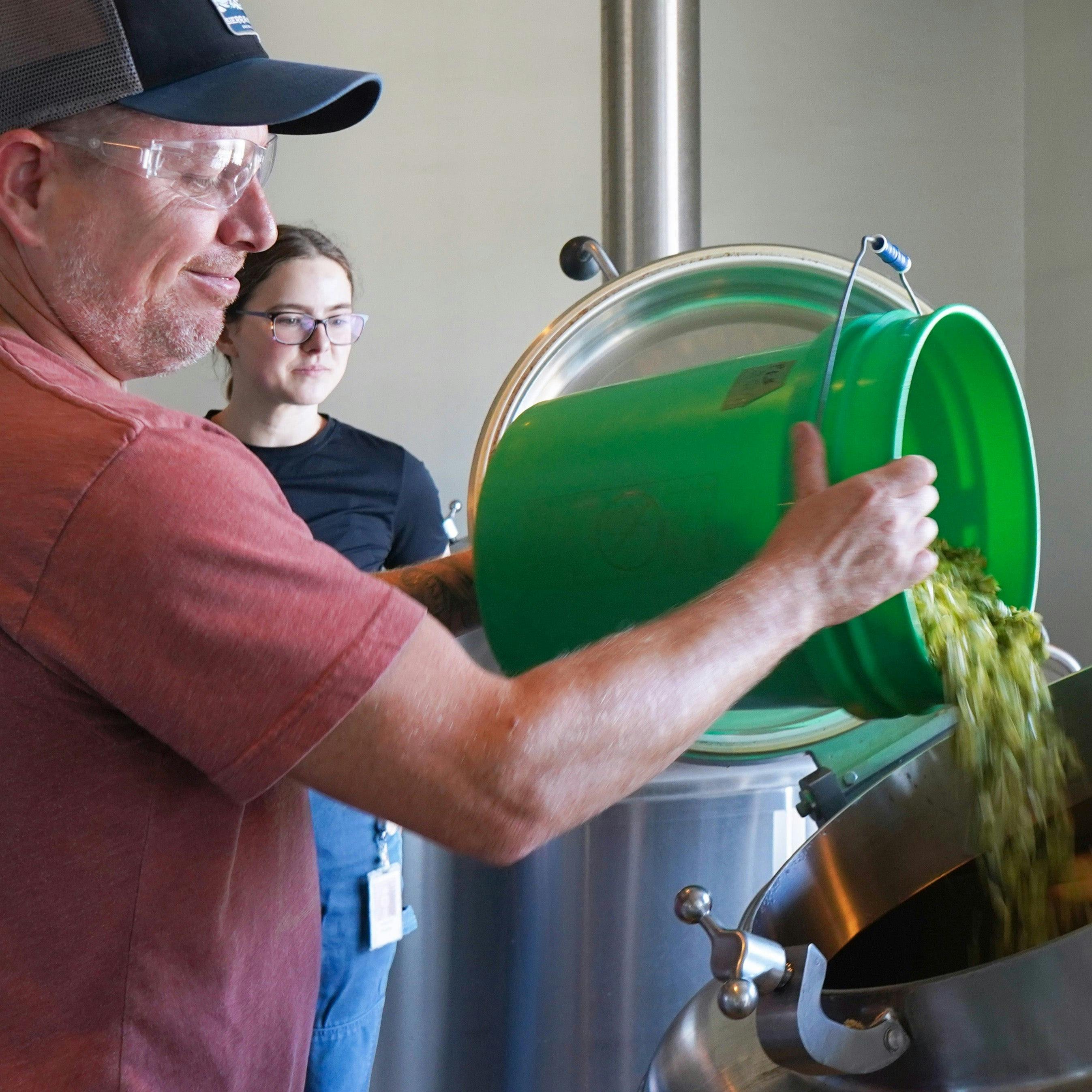 A brewer dumps a bucket of hops during the brewing process for the CCBA West Coast IPA from Sierra Nevada.