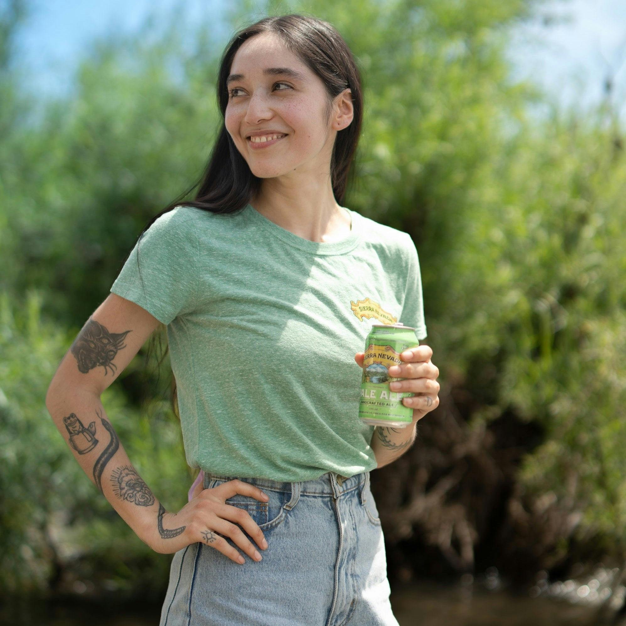 Sierra Nevada Brewing Co. Women's Pale Ale T-Shirt worn by a woman standing on the bank of a river enjoying a Pale Ale