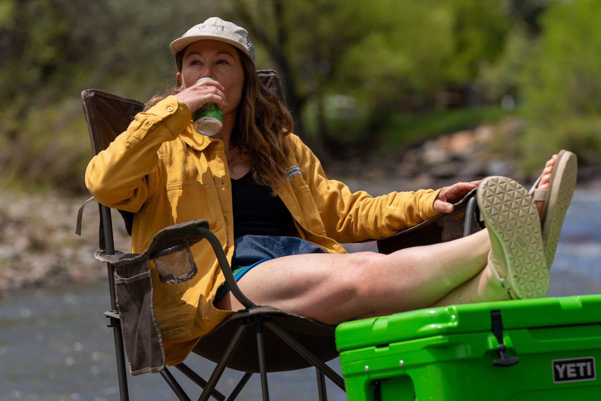 Someone drinking can of Pale Ale with feet on a Yeti cooler